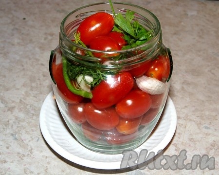 Зелень, чеснок и горошинки перца выложить в банку с помидорами.
