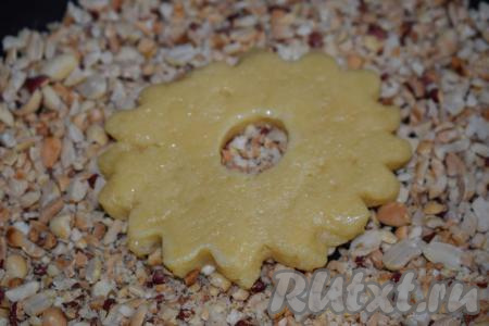 Далее берем каждое кольцо в ладошку и стороной, смазанной яйцом, обмакиваем в дроблёный арахис, слегка вдавливая тесто в орехи.