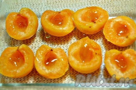 Абрикосы переложить в огнеупорную форму. В каждую половинку абрикоса положить по капельке меда.