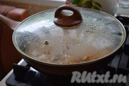 В сковороду добавляем целые очищенные зубчики чеснока. Обжариваем чеснок с курицей и овощами, примерно, минуту. Затем вливаем 2 стакана воды и тушим овощи с курицей на медленном огне с момента закипания, примерно, 12 минут, накрыв сковороду крышкой.