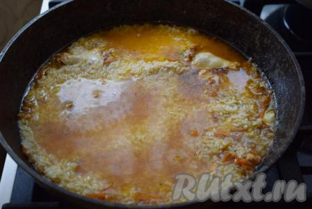 По прошествии времени добавляем в сковороду наш замоченный рис, предварительно слив воду, в которой мы его замачивали. Разравниваем рис ложкой по всей поверхности сковороды.