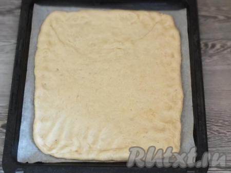 Возьмите противень и застелите пергаментом. Большую часть теста раскатайте в пласт толщиной 0,5 см, переложите на противень.