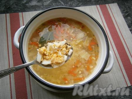 Когда суп с капустой проварится 10 минут, выложить в него обжаренные лук с морковью, перемешать, добавить лавровый лист и рубленные варёные яйца.