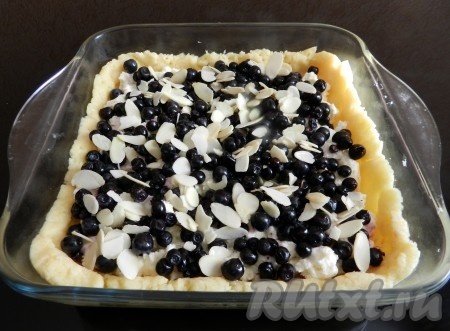 Сверху разложить чернику. Ягоды я сверху посыпала миндальными хлопьями, но это необязательно. Выпекать&nbsp;песочный пирог с творогом и черникой в разогретой до 200 градусов духовке 25-30 минут.