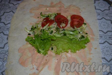 Берём 1 часть лаваша и смазываем по центру, примерно, 2 столовыми ложками приготовленного соуса для шавермы, оставляя края лаваша чистыми. Далее кладём 1/4 часть капустного салата, рядом выкладываем по 3 кружочка помидора и по листу салата.