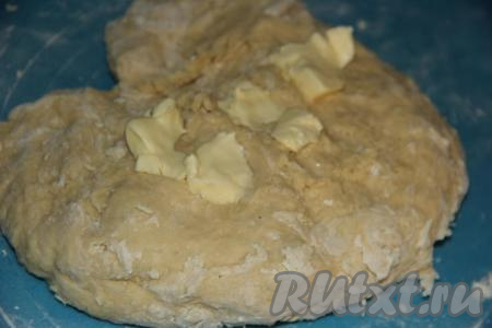 Добавить 80 грамм мягкого сливочного масла, разделённого на кусочки, и аккуратно его вмесить в тесто.