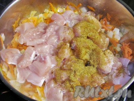 Затем в сковороду с морковкой и луком кладём кусочки куриного филе, посыпаем приправой хмели-сунели и жарим, постоянно перемешивая, на достаточно сильном огне, примерно, 1,5 минуты.
