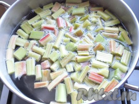 В просторную кастрюлю налейте 2 литра воды, добавьте сахар, поставьте на огонь, доведите до кипения. После в воду с сахаром выложите нарезанный ревень, доведите до кипения, а затем на среднем огне проварите 7 минут.