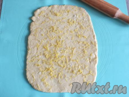 Смажьте рабочую поверхность 1 столовой ложкой растительного масла. Раскатайте тесто в пласт толщиной 2-3 мм. Смажьте тесто 2 столовыми ложками растительного масла, посыпьте 2 столовыми ложками сахара и сверху натрите на тесто цедру одного лимона.