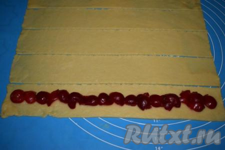 Нарезаем каждый пласт на 5 полос шириной 5 см. Далее на каждую полосу теста выкладываем вишни, как на фото.
