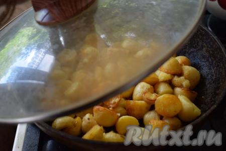 Жарим молодую картошку в кожуре, накрыв сковороду крышкой и периодически перемешивая, до готовности. Продолжительность приготовления у всех будет разной, так как многое зависит от сорта картофеля, его размера, диаметра сковороды и во сколько слоёв вы выложите клубни. В среднем на жарку картошки по этому рецепту уходит 35-40&nbsp;минут.