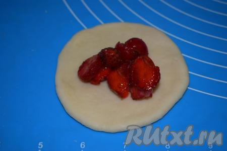 Раскатываем каждый шарик в лепёшку и кладём в середину 1 столовую ложку с горкой клубничной начинки.