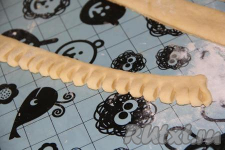 Взять одну полоску теста, с помощью ножниц сделать надрезы по всей длине полоски.