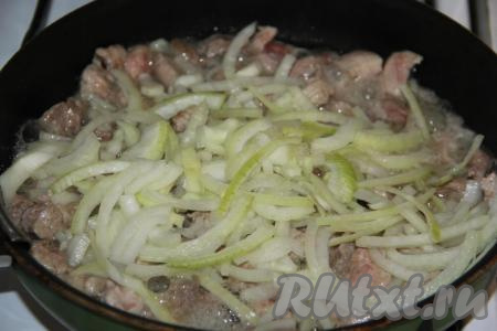 Обжарить кусочки свинины на среднем огне, иногда перемешивая, в течение 5 минут. Почистить и нарезать полукольцами луковицу, а затем выложить в сковороду со свининой.