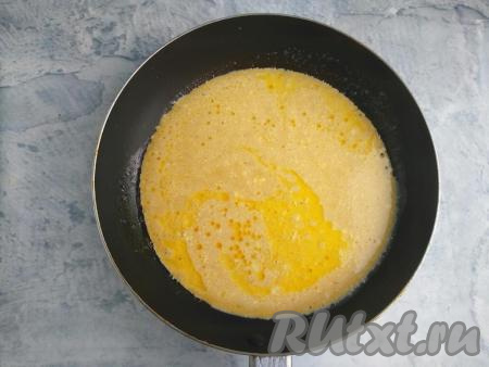 Сковороду с растительным и сливочным маслом нагреть. Вылить омлетную смесь и равномерно её распределить по поверхности. Накрыть сковороду крышкой и жарить омлет на минимальном огне до устойчивой структуры (около 4-5 минут).