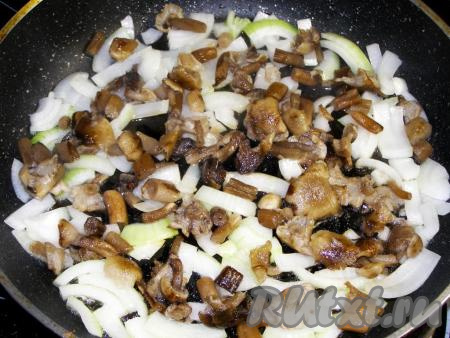 В сковородку наливаем подсолнечное масло и выкладываем в неё лук и грибы. Обжариваем на сильном огне, помешивая, пока лук не станет полупрозрачным.