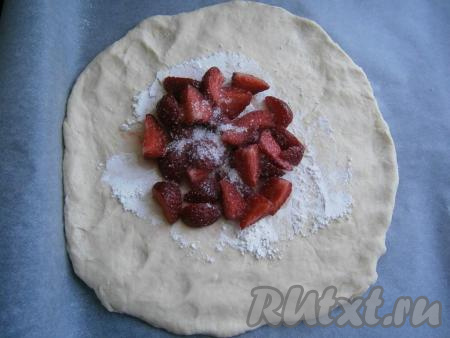 Тесто разделить на 2 части. Одну часть теста раскатать в лепёшку толщиной около 0,5 см. Центр лепешки посыпать крахмалом и выложить разрезанную на 4 части свежую клубнику. Посыпать клубнику сахаром.