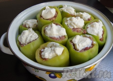 Поверх перцев равномерно разложить сметану. Прикрыть кастрюлю крышкой и томить фаршированные перцы с момента закипания воды на среднем огне минут 50.