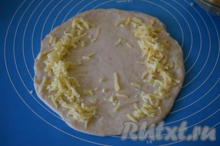 Далее каждый кусок теста раскатываем в круглую лепёшку диаметром, примерно, 24 см. Начинку визуально делим на 4 части для приготовления 4 хачапури. Далее часть начинки выкладываем на края теста (как на фото).