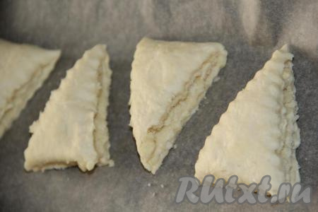 Выложить треугольнички на противень, застеленный пергаментом.