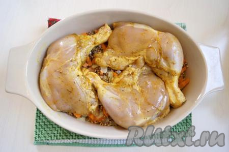 Перемешать гречку с овощами и разровнять. Сверху выложить куриные окорочка.