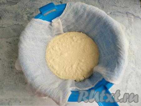 Дуршлаг застелить 2-3 слоями марли так, чтобы концы марли свисали с дуршлага. Поставить застеленный дуршлаг на кастрюлю, в которую будет сливаться лишняя жидкость. Вылить творожную массу в застеленный дуршлаг. Накрыть творожную массу свисающими концами марли, немного отжать, а затем сверху поставить пресс (прессом может быть, например, банка с водой) и оставить на 1 час.