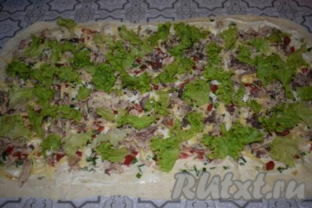 Листья салата тщательно промываем под проточной водой, обсушиваем и разрываем на мелкие кусочки, а затем раскладываем по лавашу с начинкой.