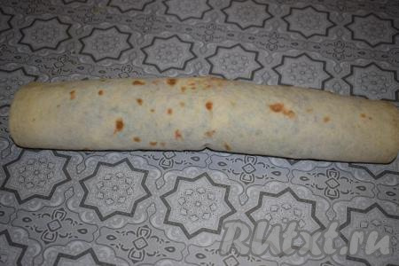 Далее плотно сворачиваем наш лаваш с начинкой в рулет, скручивая широкую сторону.