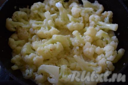 В сковороду с цветной капустой и луком вливаем молоко, аккуратно перемешиваем, уменьшаем огонь до самого слабого.