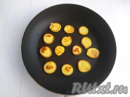Жарить на среднем огне в течение 1 минуты (до золотистого цвета) с одной стороны, затем перевернуть и готовить до золотистости с другой стороны. Готовые мини панкейки снять со сковороды, переложить на тарелку. Таким образом пожарить все панкейки.