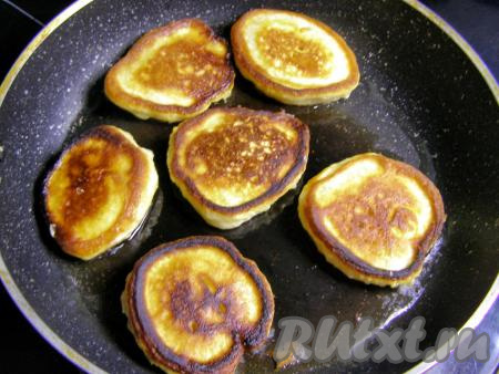 Переворачиваем оладьи лопаткой и продолжаем жарить с другой стороны около минуты, затем перекладываем готовые оладушки на тарелку. Перед тем как выложить в сковородку следующую порцию теста, подливаем на сковороду немного растительного масла.