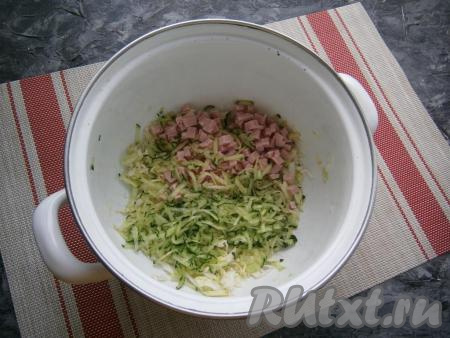 Добавить в кастрюлю нарезанную небольшими кубиками варёную колбасу и натёртые на крупной тёрке огурцы.