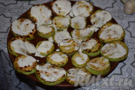 Готовим чесночный соус, для этого в миску кладём сметану (или майонез), молотый чёрный перец и натёртый на мелкой терке сыр, добавляем пропущенный через пресс чеснок, если нужно, подсаливаем, по вкусу и перемешиваем. Выкладываем обжаренные кабачки на блюдо для подачи и смазываем каждый кружочек чесночным соусом. Сверху кладём листочки базилика (если листья базилика крупные, разрежьте их на части).