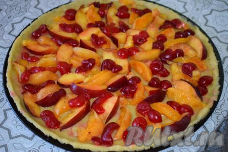 На тесто выкладываем дольки фруктов и раскладываем ягоды&nbsp;по всему периметру пирога. Присыпаем пирог сахаром.