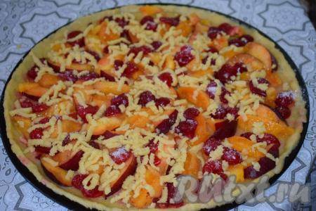 Натираем на крупной тёрке оставшийся маленький кусочек теста и&nbsp;распределяем натёртое тесто по всей поверхности песочного пирога поверх фруктов и ягод.