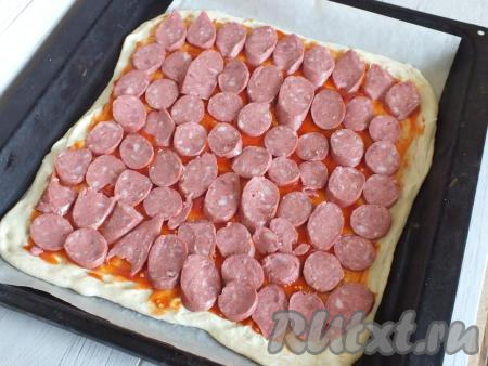 Разложите на томатный соус нарезанную колбасу.