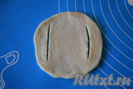 Далее каждый шарик раскатываем в лепёшку и делаем&nbsp;2 надреза с боков, как на фото.