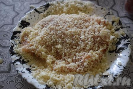 Затем обваливаем куриное филе в сухарях с двух сторон, плотно вдавливая отбивную в сухари. Таким образом подготавливаем все шницели.