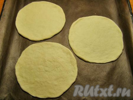 К этому времени тесто уже должно будет подойти и увеличиться в объёме, примерно, в два раза. Разминаем его и делим на 8-9 одинаковых кусочков. Присыпаем доску мукой и раскатываем каждый кусочек теста в тонкую круглую лепёшку диаметром 12-14 см. Перекладываем несколько лепёшек на противень, застеленный ковриком для выпечки (или пекарской бумагой).
