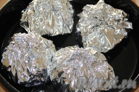 Завернуть фольгу в виде "бомбочки", закрепив края сверху. Аналогично завернуть в фольгу оставшиеся куриные бёдра и картошку. Выложить мясо с картофелем, завёрнутые в фольгу, на противень и поставить в разогретую духовку. Готовить блюдо в течение&nbsp;50 минут при температуре 220 градусов.