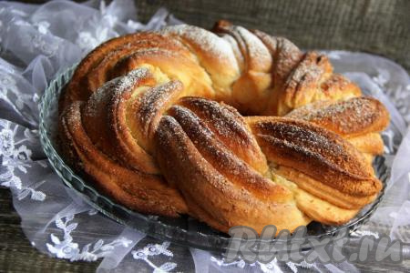 Готовый пирог слегка остудить и переложить с противня на тарелку. Перед подачей можно присыпать сдобную плетёнку сахарной пудрой.