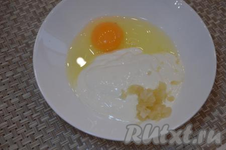 В отдельную посуду добавить 1 сырое яйцо, 2 пропущенных через пресс зубчика чеснока, 3-4 столовых ложки сметаны.