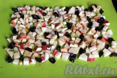 Для приготовления начинки бисквитного рулета быстро нарежьте яблоки на небольшие кубики (или дольки). Я дополнительно ещё добавила чернослив, нарезанный на 2-4 части, но это по желанию. На противне разместите силиконовый коврик (или бумагу для выпечки), выложите сверху нарезанные фрукты, отступив 3-4 сантиметра от края. Посыпьте яблоки корицей. Если у вас не очень сладкие яблоки, то можно их дополнительно присыпать 1 столовой ложкой сахара.