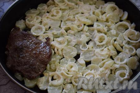 На картофель выкладываем половину лука со сметаной. На лук кладём обжаренные отбивные из говядины.