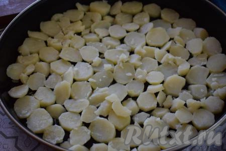 В форму для запекания (или на противень) кладём кусочки сливочного масла, сверху выкладываем кружочки картофеля.