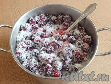 Вишню переложите в просторную кастрюлю с толстым дном, засыпьте ягоды сахаром, перемешайте и оставьте на 1-3 часа при комнатной температуре.