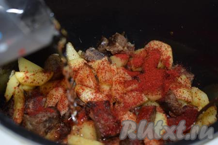 По прошествии времени добавляем в чашу паприку и вливаем тёплую кипяченую воду (воды добавляем столько, чтобы она слегка покрывала картофель с мясом, примерно, 350 мл). Даём закипеть воде и выключаем режим "Жарка".