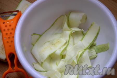 Для этого блюда нужно брать молоденькие кабачки с тонкой кожурой (её можно не срезать) и мелкими семечками. Кабачки вымыть, затем их обсушить, отрезать кончики с двух сторон. С помощью овощечистки кабачки нарезать на тонкие полоски (слайсы), как на фото, посолить, хорошо перемешать и оставить при комнатной температуре на 30 минут.