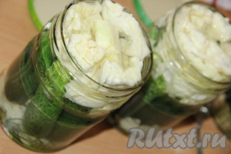 Залить банки с огурцами и капустой горячим маринадом до самого верха.