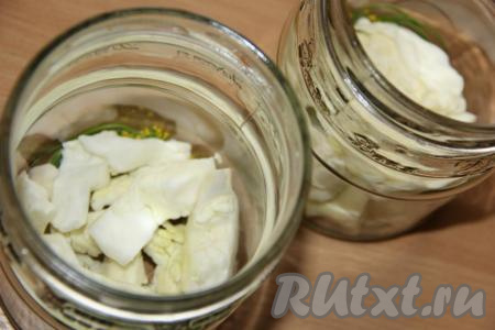 Капусту нарезать крупными дольками. Часть нарезанной белокочанной капусты выложить на дно банок.